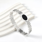 Geweven mesh-armband met zwarte ronde oliedruppels.
