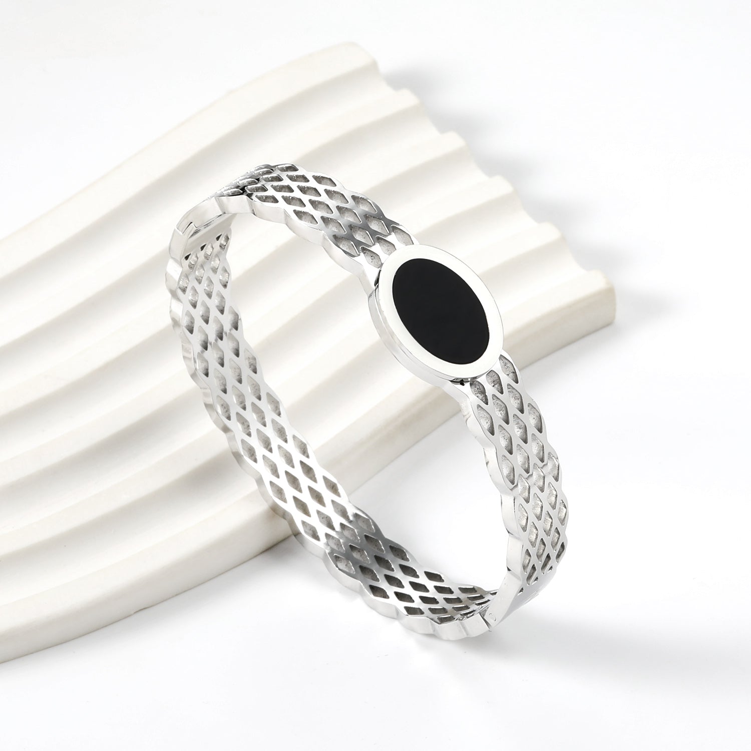 Geweven mesh-armband met zwarte ronde oliedruppels.