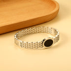 Geweven mesh-armband met zwarte ronde oliedruppels.