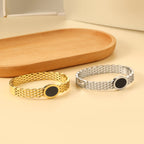 Geweven mesh-armband met zwarte ronde oliedruppels.