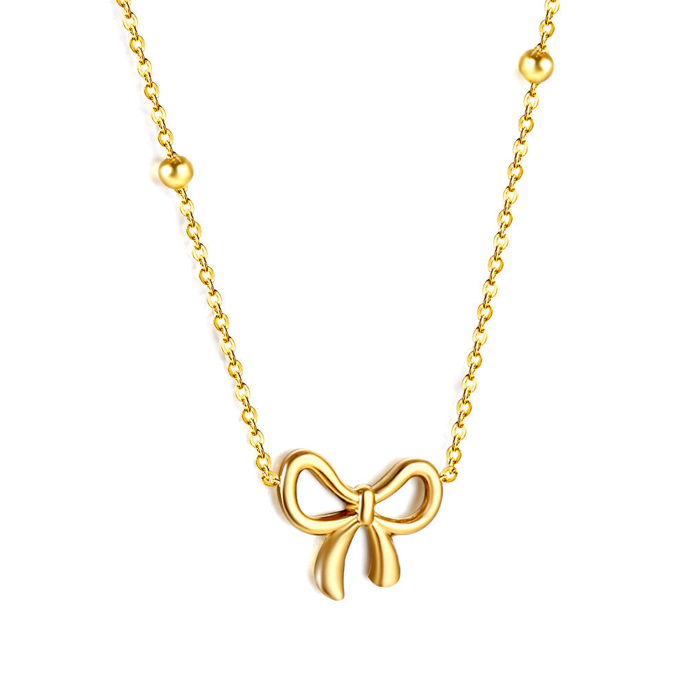 Close-up of JCS Bow Pendant Necklace in gold-tone stainless steel with a delicate bow charm on an adjustable 40+5cm chain.